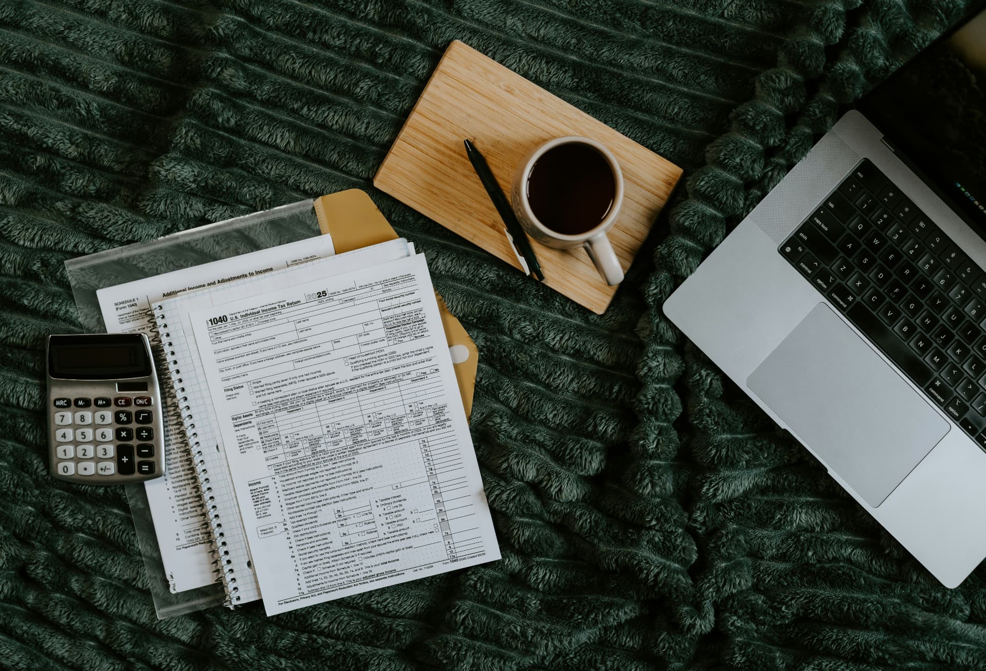 Tax return paperwork, calculator and laptop on a desk